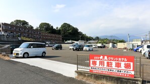 A parking lot with various vehicles, including cars and a bus, and a sign indicating a parking fee of 20,000 yen. - Kanoya Daikoku Grand Hotel (Kanoya)