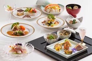 Un assortiment de plats présentés sur un plateau, notamment des sushis, des sashimis et un dessert.