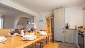A dining area with a wooden table set for four, including wine glasses and plates. - Twitchers Cottage, Titchwell, Norfolk (Titchwell)