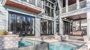 A modern house with a swimming pool, large windows, and a covered outdoor area. - Vermillion Sunsets | Lakefront Architectural Gem-Pool/Hot Tub/New 6 Seat LSV (Santa Rosa Beach)