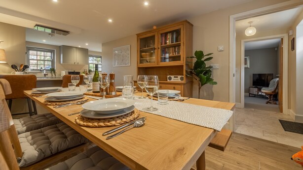 A dining area with a wooden table set for four, surrounded by cushioned seating.
