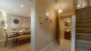 A dining area with wooden furniture, a staircase, and wall-mounted artwork.