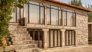 A stone building with a staircase leading to a second-floor entrance, large windows, and a tiled roof. - Casa da Eira - Casa Rural com Piscina Privada (Oliveira (São Pedro))