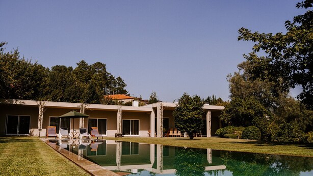 A modern house with a swimming pool, a patio with chairs, and a well-maintained lawn. - Casa da Eira - Casa Rural com Piscina Privada (Oliveira (São Pedro))