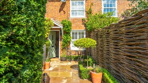 A brick house with a tiled roof, a satellite dish, a white window, and a garden with a table and chairs. - Pond Cottage, Docking, Norfolk (Docking)