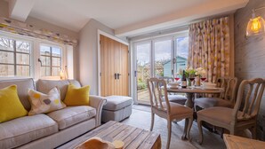A cozy living room with a sofa, coffee table, and dining table set for a meal. - Pond Cottage, Docking, Norfolk (Docking)