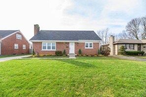 A two-story brick house with a front lawn, a front door, and a chimney.