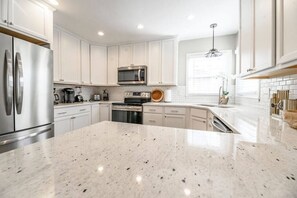 Una cocina moderna con armarios blancos, electrodomésticos de acero inoxidable y encimera de granito.