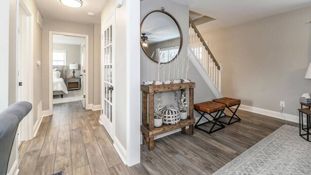 Un couloir avec un escalier, un banc en bois et un miroir accroché au mur.