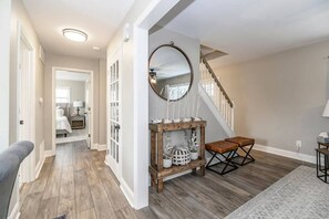 A hallway with a staircase, a wooden bench, and a mirror on the wall.