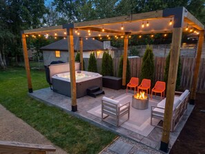 Eine Terrasse im Freien mit Whirlpool, Sitzgelegenheiten und Lichterketten.