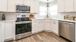 A kitchen with white cabinets, stainless steel appliances, and a wooden floor.