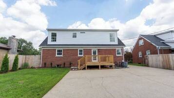 A two-story house with a wooden deck, brick exterior, and a clear sky.