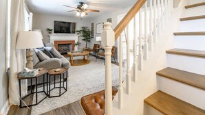 A living room with a fireplace, a sofa, a coffee table, and a staircase.