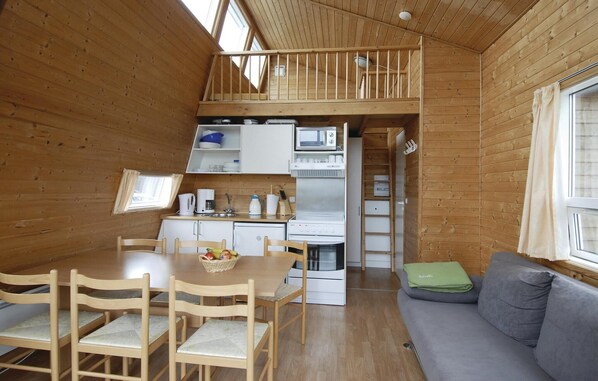 Une cuisine compacte avec un coin repas, une chambre en mezzanine et un canapé.