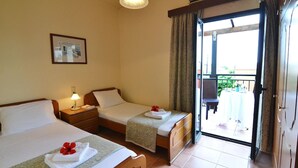 A hotel room with two beds, a small table with a lamp, a picture on the wall, and a balcony with a table and chairs. - Christina III (Πενταμόδι, Κρήτη)