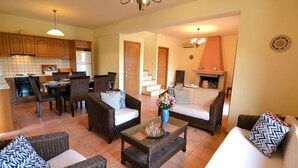 A spacious living area with a dining table, sofas, and a fireplace. - Christina III (Πενταμόδι, Κρήτη)