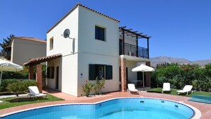 A two-story house with a swimming pool, outdoor seating, and a view of mountains. - Christina III (Πενταμόδι, Κρήτη)