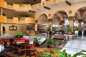 Relax in the spacious lobby with comfortable seating and lush greenery, surrounded by distinctive arches and columns.