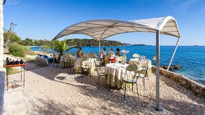 An outdoor dining area with tables and chairs under a canopy, overlooking a body of water. - STUDIO "GREEN GARDEN" in own SOUTH GARDEN- balcony, 5 minutes walk from the beach, Rovinj  (Rovinj)