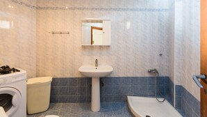 Un baño con lavadora, lavamanos y bañera.