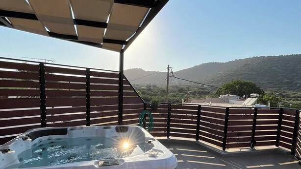Un jacuzzi en un porche cubierto con vistas a un paisaje montañoso.