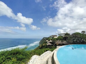 Ein Pool mit Blick auf den Ozean und eine tropische Landschaft.