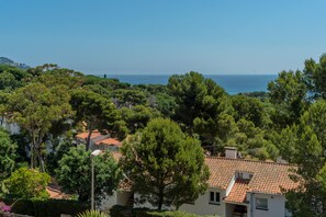 A coastal residential area with houses surrounded by dense greenery and a clear view of the sea.