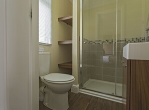 Un baño con inodoro, ducha con mampara de vidrio y lavamanos.