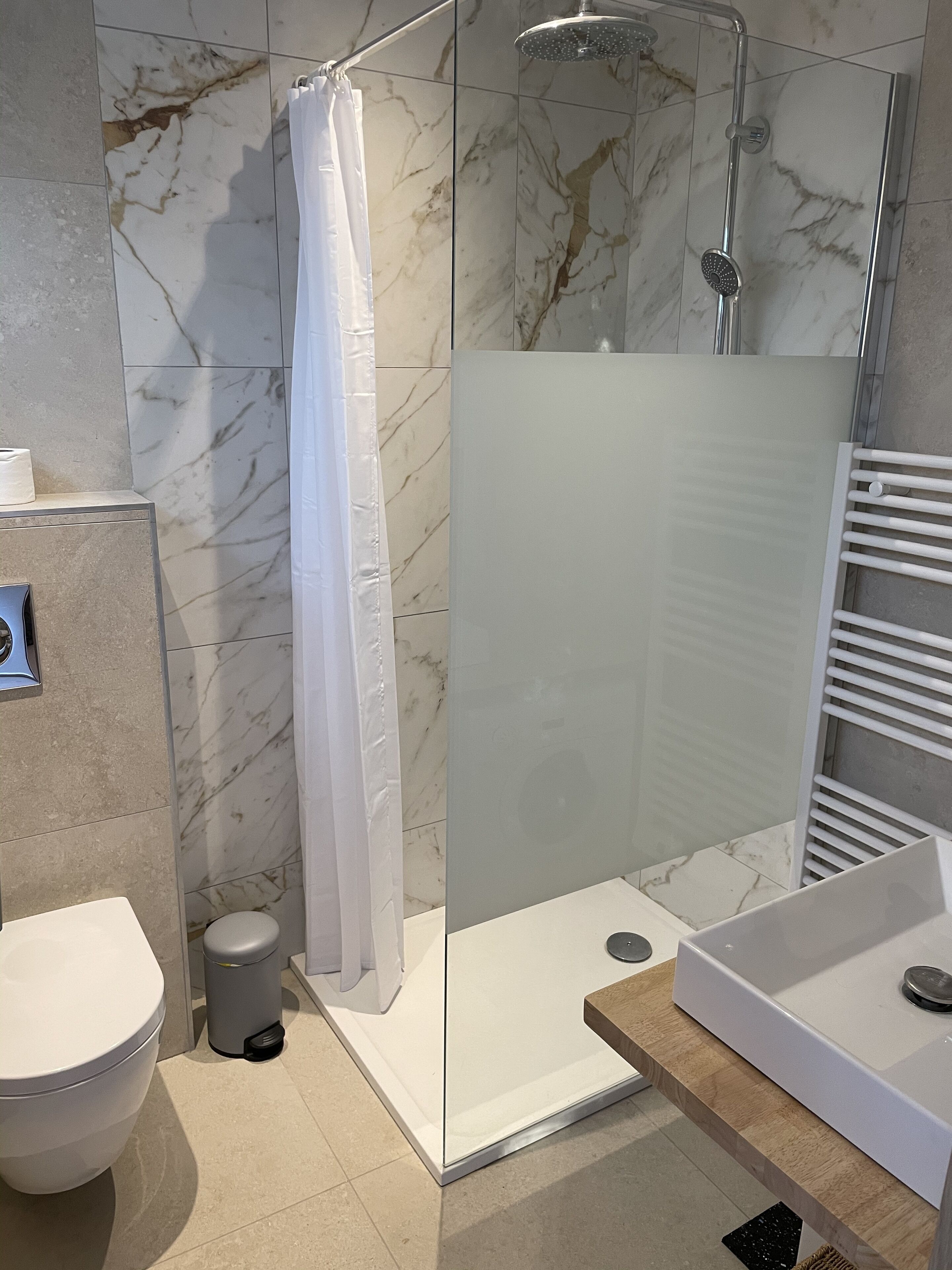 Un baño moderno con ducha vidriada, inodoro y lavamanos.