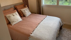 Ein Schlafzimmer mit einem Bett, einem Fenster und Blick auf Grün.