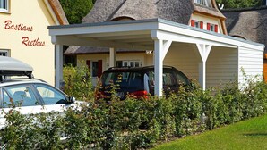 A building with a covered parking area and a car parked inside. - Very spacious thatched house with lots of comfort on a large plot in a peripheral location (Glowe)