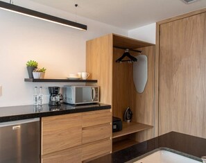 Een moderne keuken met een ingebouwde magnetron, koffiezetapparaat en een hangrek.