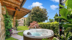 A hot tub in a garden with a wooden pergola, stone pathway, and lush greenery. - Villa Clara with Outdoor Jacuzzi few km from the Sea, Pietrasanta, Italy (Pietrasanta)