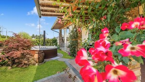 A garden with a hot tub, a stone wall, and a pergola. - Villa Clara with Outdoor Jacuzzi few km from the Sea, Pietrasanta, Italy (Pietrasanta)