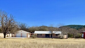 A rural property with a single-story house, a red barn, and a large open field. - Concan River Ranch ~ 1,000' Private Frio River! Mtn. Views, Pet & Polaris OK. (Concan)