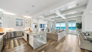 A spacious kitchen with a large island, modern appliances, and a view of the ocean.