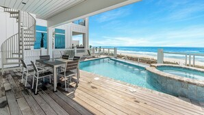 A wooden deck with a pool, a spiral staircase, and a view of the ocean.