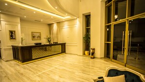 A spacious lobby with a reception desk, a dark blue sofa, and a large window.