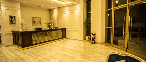 A spacious lobby with a reception desk, a dark blue sofa, and a large window.