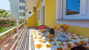 A balcony with a table set for breakfast, including croissants, coffee, and fruit. - Holiday apartment with barbecue for shared use (Crikvenica)