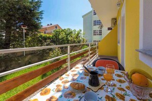 Un balcón con una mesa dispuesta para el desayuno, incluyendo pan, fruta y una cafetera.