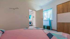 A bedroom with a bed, a wardrobe, and a door leading to another room. - Holiday apartment with barbecue for shared use (Crikvenica)