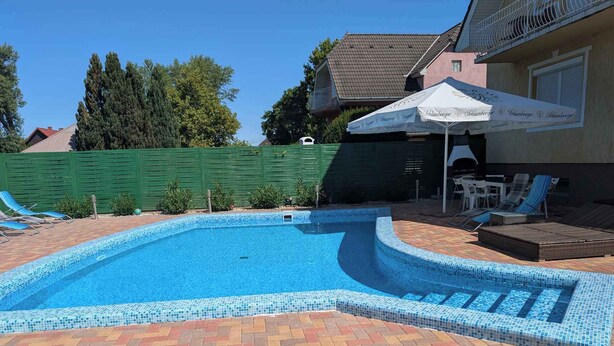 A swimming pool with a tiled edge, surrounded by a brick patio and lounge chairs.