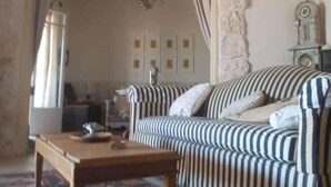 Een woonkamer met een gestreept bankje, een houten salontafel en een vloerkleed met een patroon.