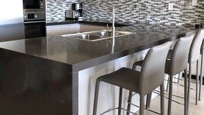 Una cocina moderna con una isla central, electrodomésticos de acero inoxidable y un salpicadero con diseño.