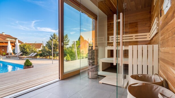 Une chambre moderne avec un mur en verre, un plancher en bois et une vue sur une piscine et un espace de détente extérieur.