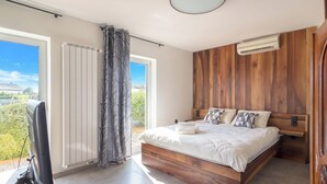 Une chambre avec un lit en bois, une télévision et une vue sur la verdure.
