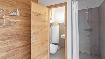 Un baño moderno con pared de paneles de madera, ducha e inodoro.