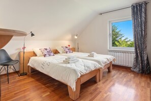 Un dormitorio con una cama, mesitas de noche, una silla, un ventanal y un radiador.